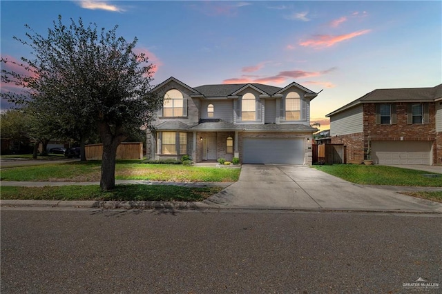 traditional-style house with a garage, driveway, and fence