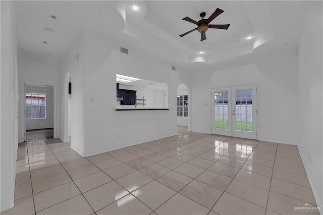 unfurnished living room featuring plenty of natural light, ceiling fan, light tile patterned floors, and a towering ceiling