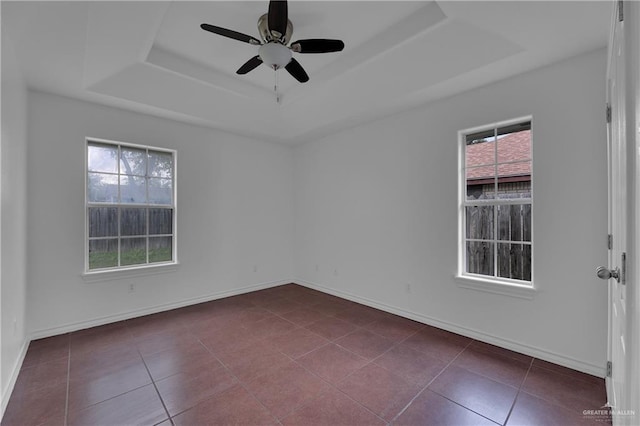 unfurnished room featuring ceiling fan, a raised ceiling, and dark tile patterned floors