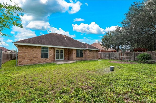 back of house featuring french doors, a patio, and a lawn