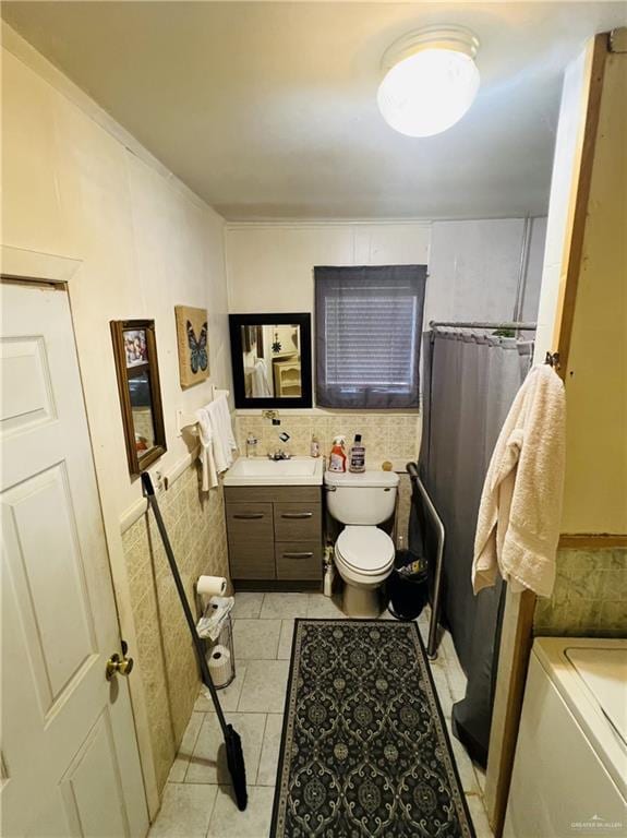 593 5th St, Raymondville, TX 78580 - bathroom featuring tile walls, toilet, vanity, tile patterned flooring, and a wainscoted wall