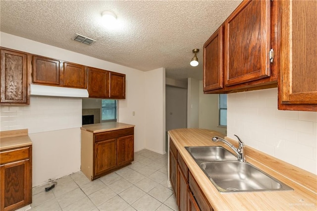 5111 Other, San Antonio, TX 78217 - kitchen with a sink, a textured ceiling, tasteful backsplash, under cabinet range hood, and light countertops