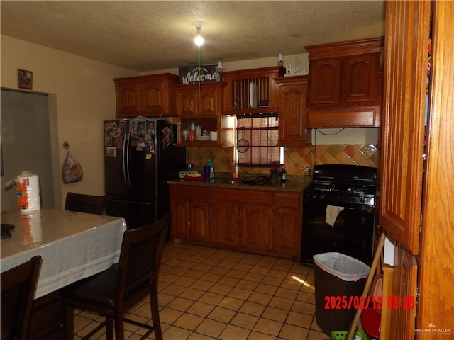 kitchen with light tile patterned floors, premium range hood, black appliances, a textured ceiling, and decorative backsplash