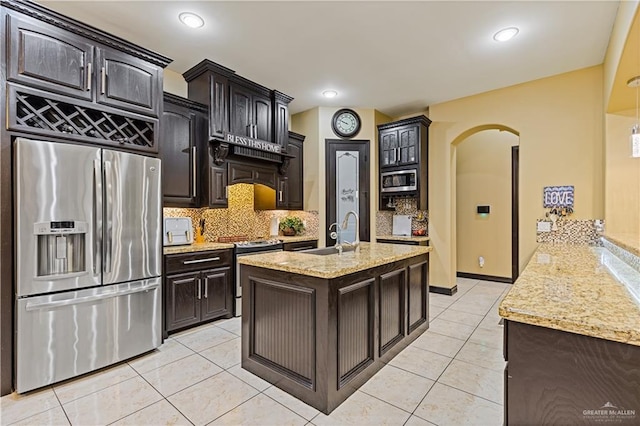 kitchen with light tile patterned floors, sink, backsplash, stainless steel appliances, and dark brown cabinetry