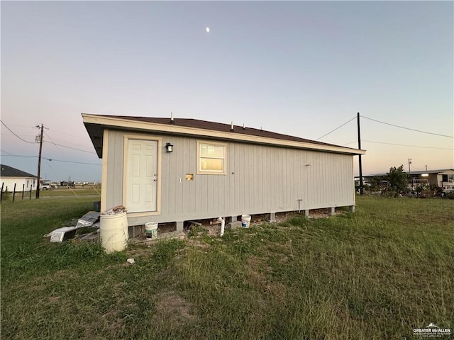 property exterior at dusk featuring a yard