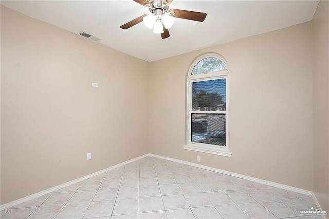 empty room featuring light tile patterned floors, baseboards, visible vents, and a ceiling fan