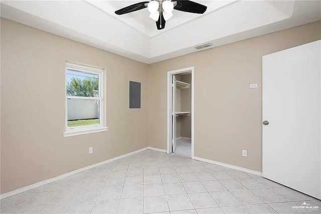 unfurnished bedroom with baseboards, a spacious closet, visible vents, and a raised ceiling