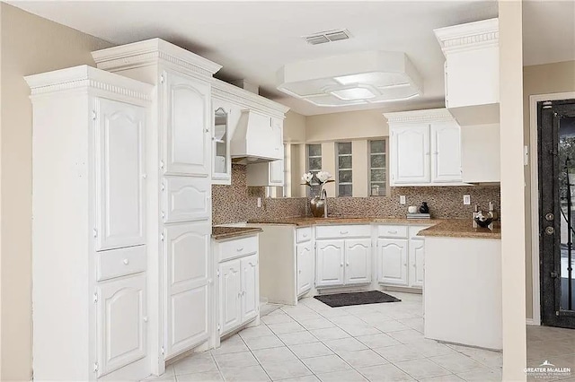 kitchen with white cabinets, premium range hood, visible vents, and tasteful backsplash