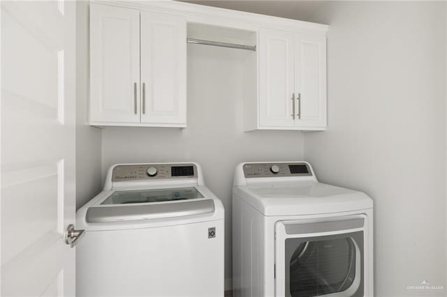 clothes washing area with cabinets and washer and dryer