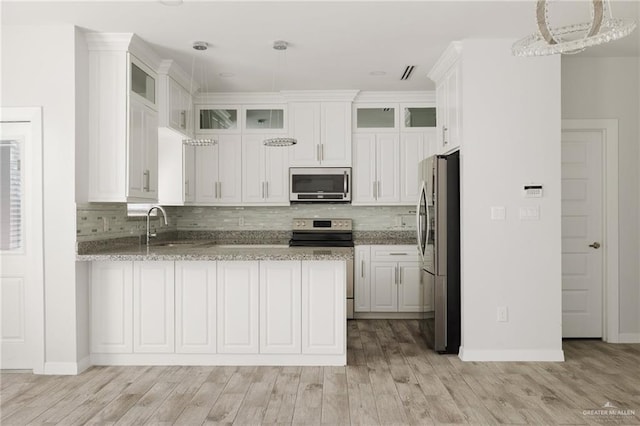 kitchen featuring pendant lighting, white cabinetry, backsplash, stainless steel appliances, and light hardwood / wood-style flooring