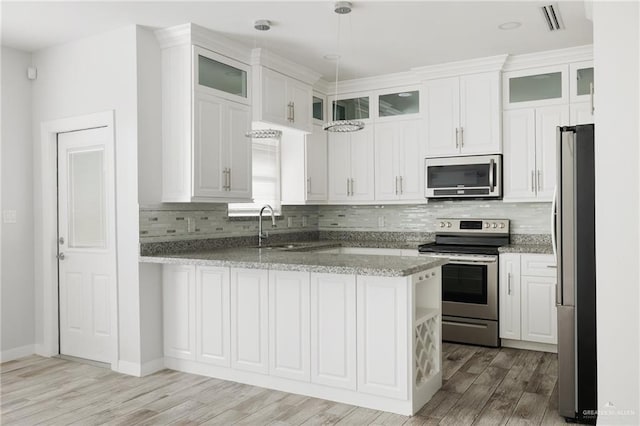 kitchen with stainless steel appliances, white cabinetry, hanging light fixtures, and kitchen peninsula