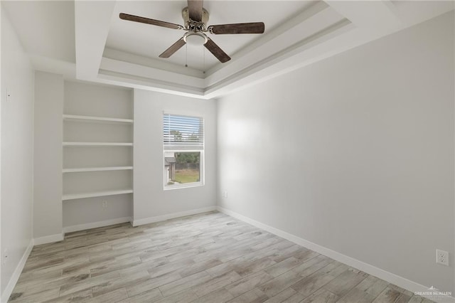 empty room featuring ceiling fan, a raised ceiling, and light hardwood / wood-style floors