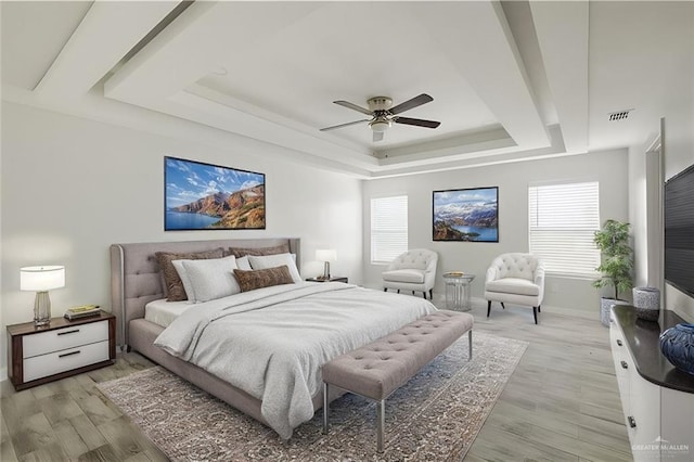 bedroom featuring ceiling fan, a tray ceiling, and light hardwood / wood-style floors