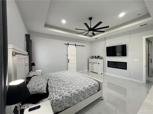 bedroom featuring a barn door, a raised ceiling, and ceiling fan