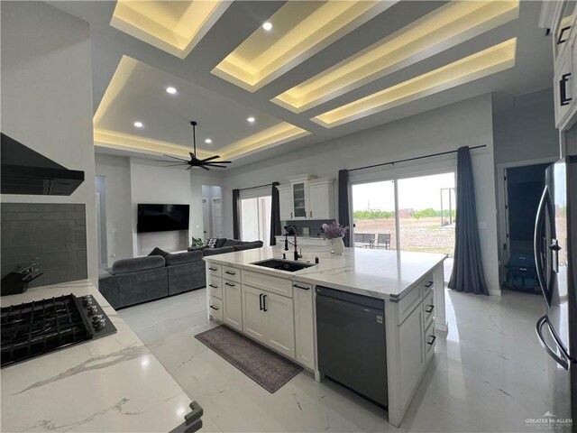 kitchen with a breakfast bar, a large island with sink, wall chimney range hood, decorative backsplash, and white cabinetry