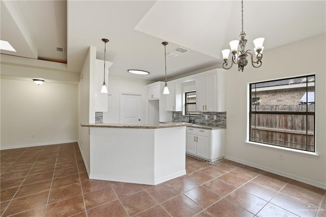 406 Casiano St, Donna, TX 78537 - kitchen featuring white cabinetry, light stone countertops, a chandelier, and decorative backsplash
