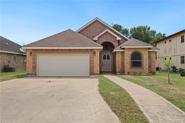 406 Casiano St, Donna, TX 78537 - traditional home featuring brick siding, a front yard, concrete driveway, and a garage