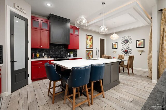 1801 Ozark Ave, Mcallen, TX 78504 - kitchen featuring a sink, light countertops, tasteful backsplash, a kitchen island with sink, and a raised ceiling
