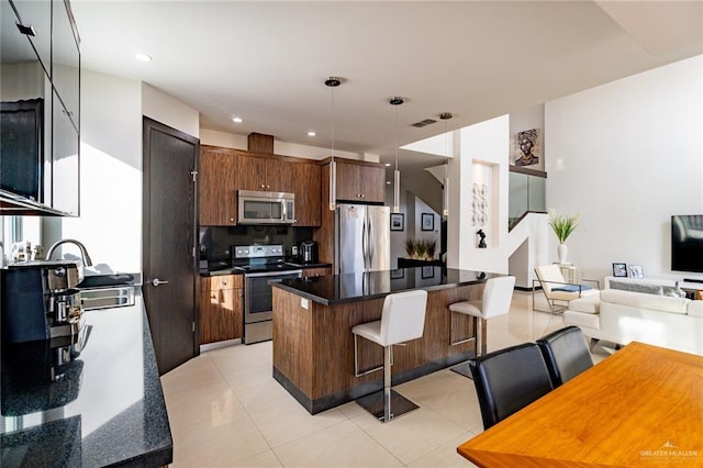 kitchen with sink, a kitchen breakfast bar, stainless steel appliances, a center island, and dark brown cabinetry