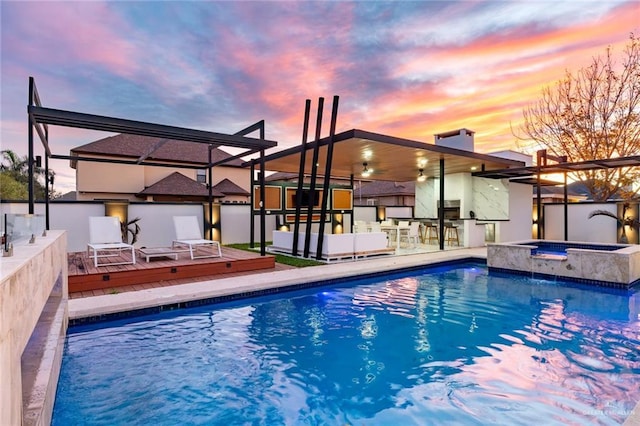 pool at dusk featuring an in ground hot tub and a deck