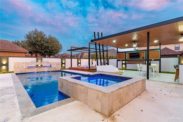 pool at dusk featuring an in ground hot tub and a patio area