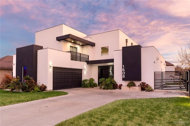 contemporary home featuring a garage, a balcony, and a lawn