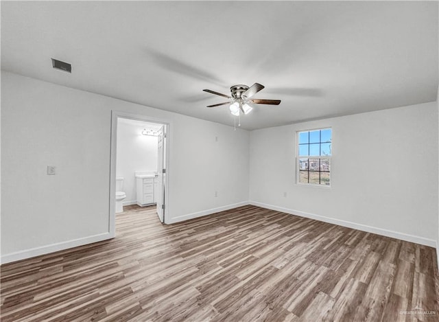 empty room with visible vents, ceiling fan, baseboards, and wood finished floors