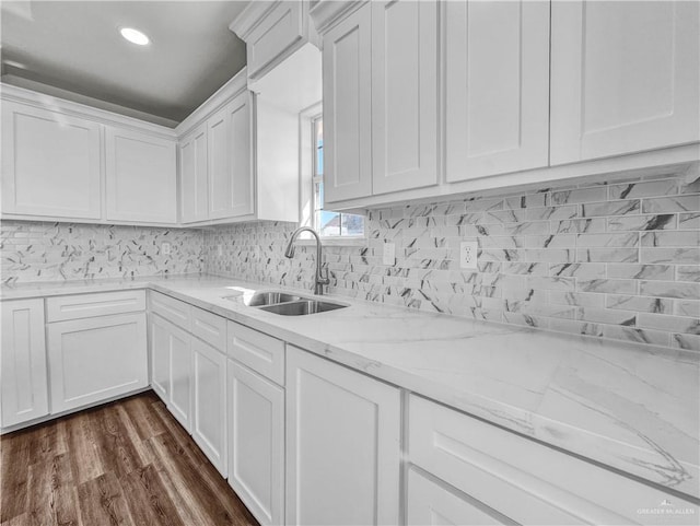 kitchen with tasteful backsplash, white cabinets, dark wood finished floors, and a sink