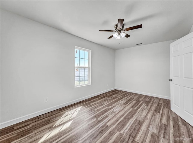 empty room with visible vents, baseboards, wood finished floors, and a ceiling fan