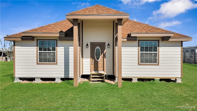 back of property featuring entry steps, a yard, and roof with shingles