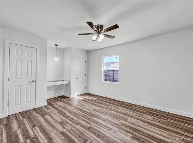 unfurnished bedroom featuring wood finished floors, baseboards, and ceiling fan