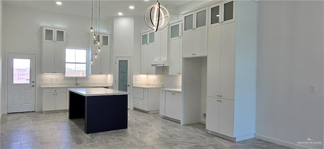 3808 Revilla St, Edinburg, TX 78542 - kitchen featuring light countertops, a high ceiling, a kitchen island, white cabinets, and glass insert cabinets