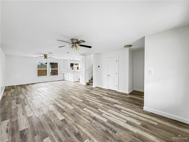 unfurnished living room featuring ceiling fan and wood-type flooring