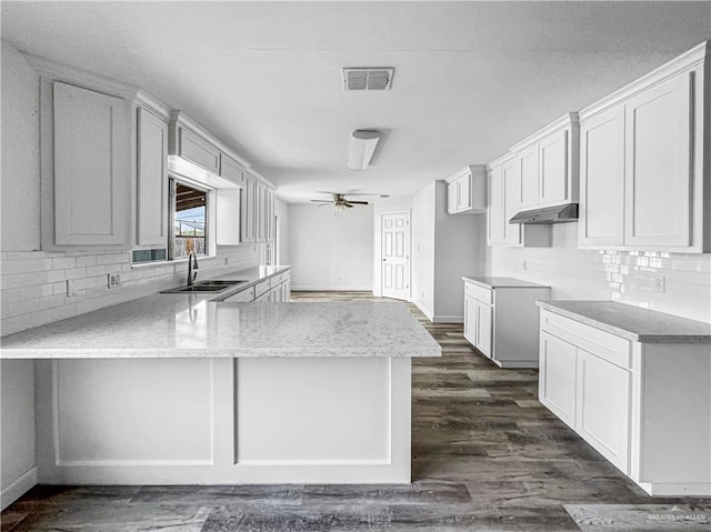 kitchen featuring kitchen peninsula, ceiling fan, dark wood-type flooring, sink, and white cabinets