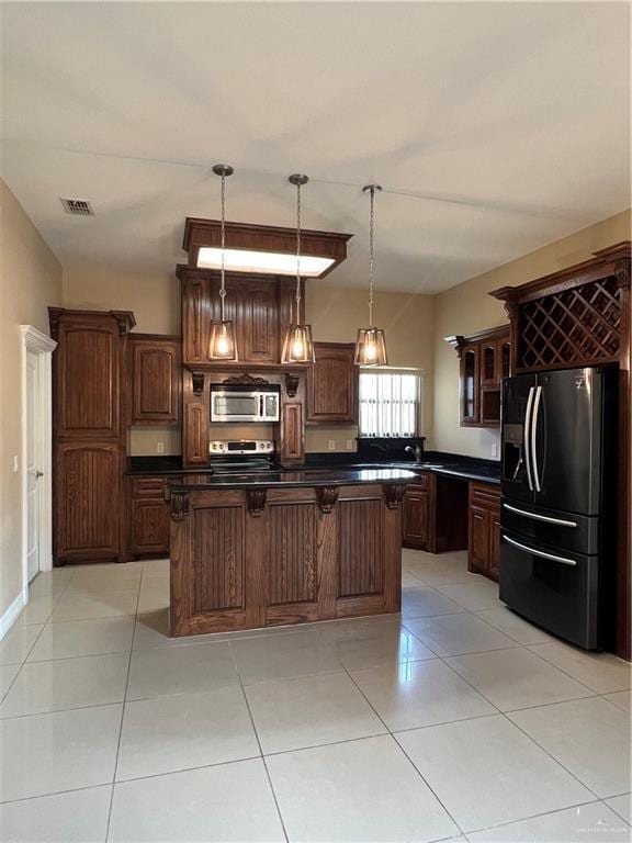 kitchen with visible vents, hanging light fixtures, appliances with stainless steel finishes, dark countertops, and glass insert cabinets