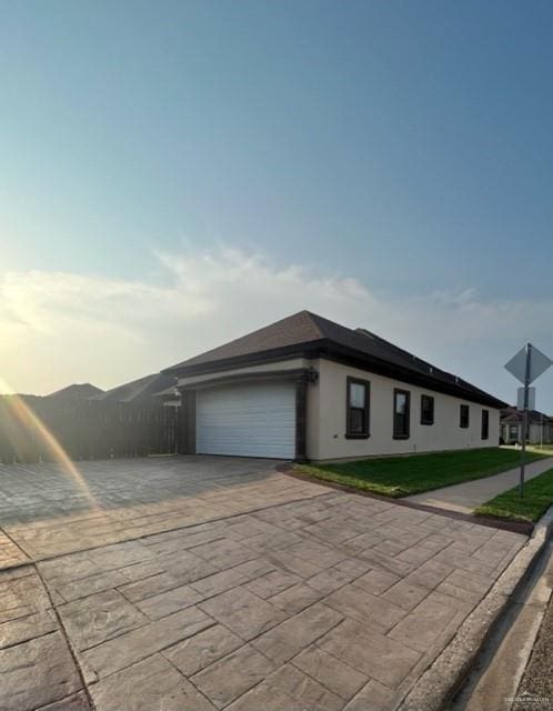 view of front of property with an attached garage, driveway, and stucco siding