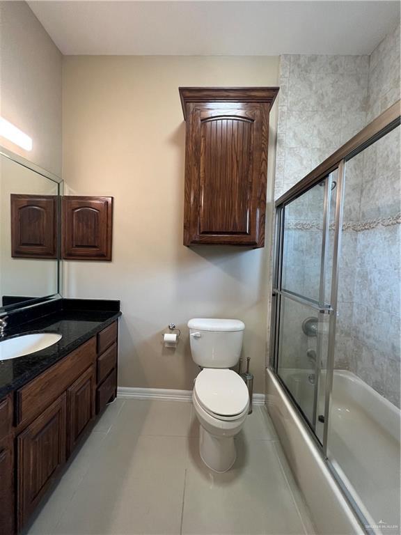 full bathroom with toilet, enclosed tub / shower combo, vanity, baseboards, and tile patterned floors