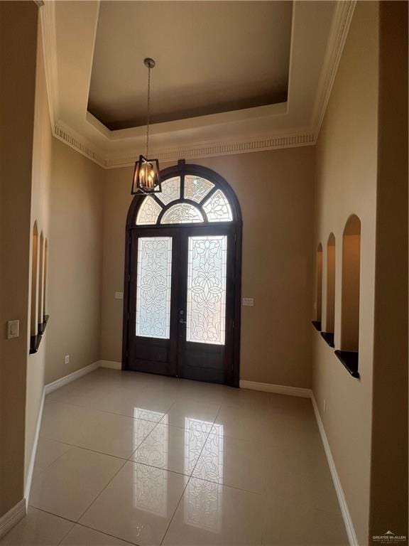 entryway featuring a chandelier, baseboards, french doors, ornamental molding, and a raised ceiling