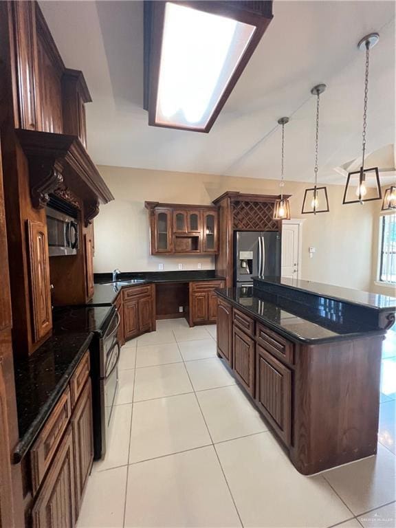 kitchen featuring dark brown cabinetry, a kitchen island, appliances with stainless steel finishes, glass insert cabinets, and light tile patterned flooring