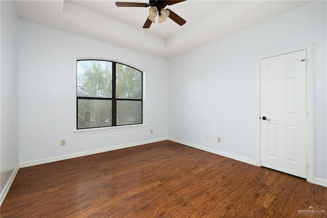 spare room featuring ceiling fan, a tray ceiling, and dark hardwood / wood-style floors