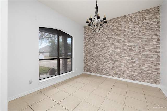 tiled spare room featuring an inviting chandelier