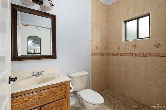 bathroom featuring toilet, vanity, and tiled shower