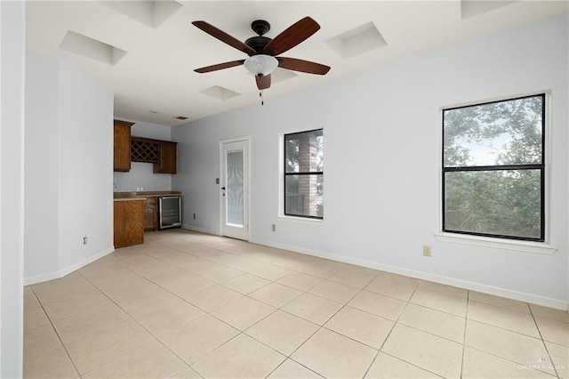 unfurnished living room with ceiling fan, light tile patterned flooring, and wine cooler