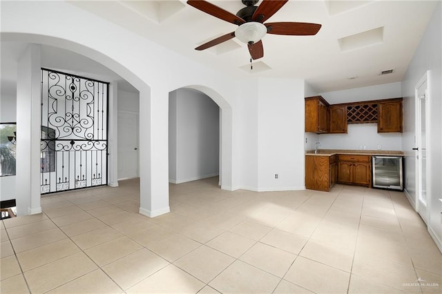 kitchen with ceiling fan, light tile patterned flooring, wine cooler, and sink