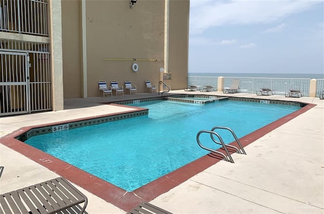 view of swimming pool featuring a patio area, a water view, and a hot tub