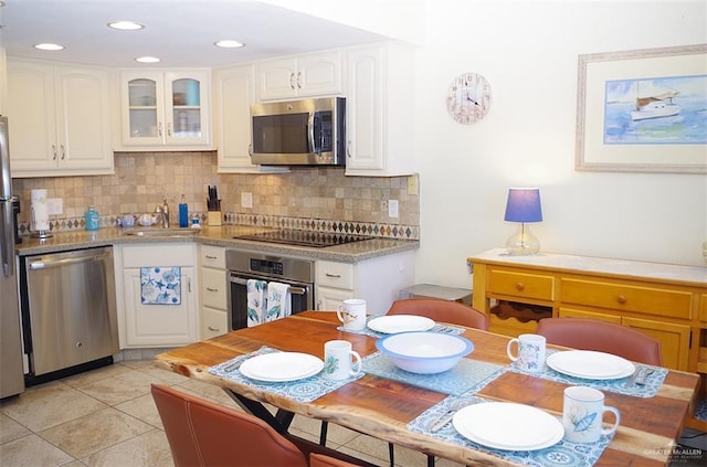 kitchen featuring backsplash, white cabinetry, light tile patterned flooring, and appliances with stainless steel finishes