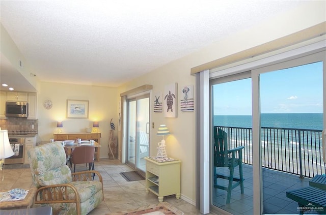 living room featuring light tile patterned floors, a textured ceiling, and a water view