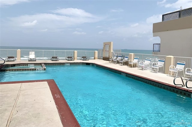 view of swimming pool featuring a water view, a patio, and a hot tub