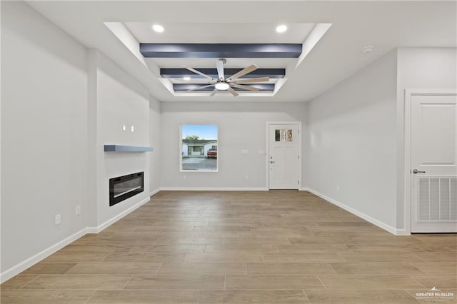 unfurnished living room with beamed ceiling, coffered ceiling, and ceiling fan