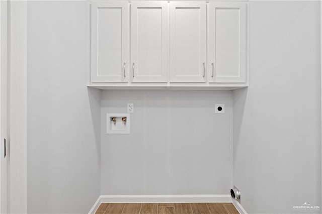 washroom featuring electric dryer hookup, hookup for a washing machine, light hardwood / wood-style flooring, and cabinets